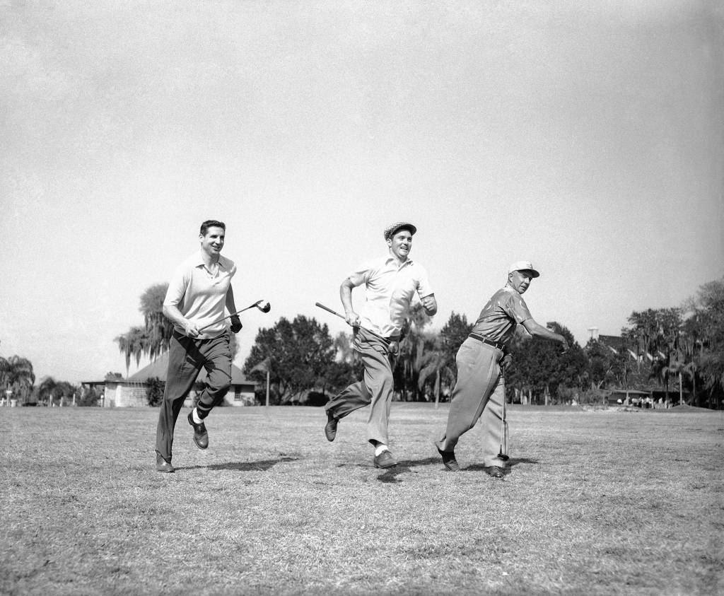 Milwaukee Braves coach Johnny Cooney (right) waves on Bobby Thomson (left) and the Phillies Earl Torgeson (center), a Snohomish High School alum, as the players run down fairway for benefit of photographers during an annual baseball players golf tourney at Tampa Golf and Country Club in 1955. (AP Photo)