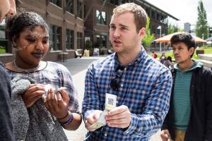 Cryptocurrency and Blockchain Club president Zachary Nelson explains to a pair of students how the currency works while handing out free cryptocurrency at the University of Washington Bothell on Wednesday, May 9, 2018 in Everett, Wa. (Andy Bronson / The Herald)