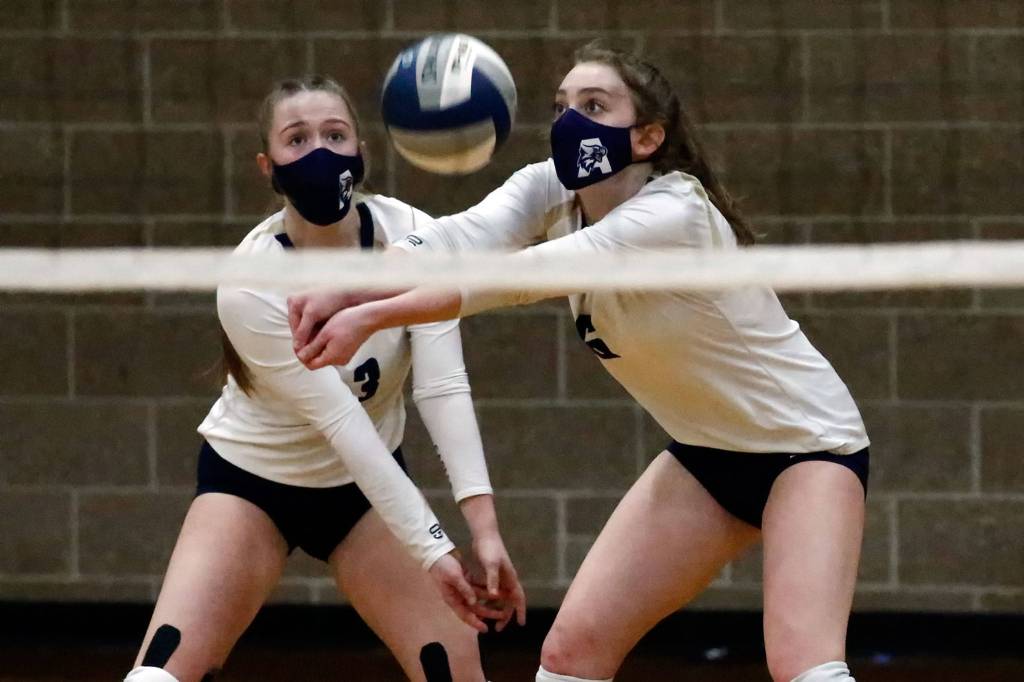 Arlingtons Paige Richards (left) and Brookelynn Ramey look to dig the ball during a March 11 game against Jackson at Arlington High School. (Kevin Clark / The Herald)