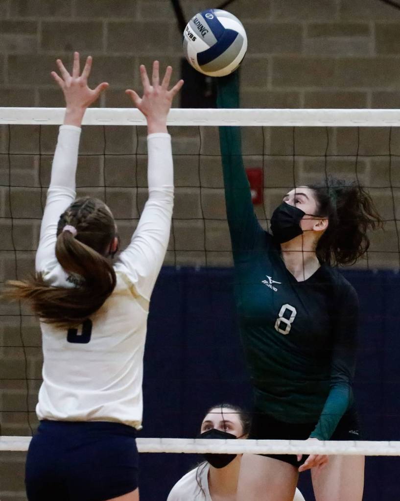 Jacksons Erin Ingram (right) spikes the ball with Arlingtons Paige Richards defending during a March 11 match at Arlington High School. (Kevin Clark / The Herald)