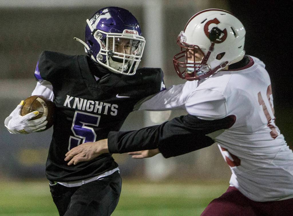 Kamiaks Dylan James (left) stiff-arms a Cascade defender during a game on April 1, 2021, in Everett. (Olivia Vanni / The Herald)