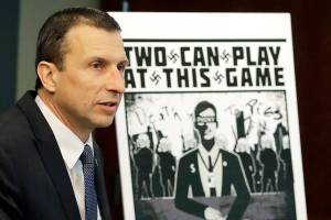FILE - In this Feb. 26, 2020, file photo, Raymond Duda, FBI Special Agent in Charge in Seattle, speaks as he stands next to a poster that was mailed earlier in the year to the home of Chris Ingalls, an investigative reporter with KING-TV during a news conference in Seattle. A federal judge declined to impose prison time Wednesday, March 31, 2021, on a former member of a neo-Nazi ring that made threats against journalists, finding that the 21-year-old, who concealed his transgender identity from his co-conspirators, had already suffered enough in his young life. (AP Photo/Ted S. Warren, File)