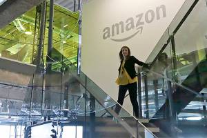 FILE - In this Sept. 27, 2017, file photo, an Amazon worker walks down steps in a company office before an event announcing several new Amazon products by the company in Seattle. Amazon plans to have its employees return to the office by fall as the tech giant transitions away from the remote work it implemented for many workers due to the coronavirus pandemic. On Tuesday, March 30, 2021, the company told employees it is planning a "return to an office-centric culture as our baseline." (AP Photo/Elaine Thompson, File)