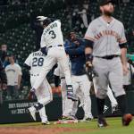 Seattle Mariners' Jake Fraley (28) is mobbed by teammates, including J.P. Crawford (3) after he was walked with the bases loaded during the tenth inning of a baseball game against the San Francisco Giants, Thursday, April 1, 2021, in Seattle. The Mariners won 8-7. (AP Photo/Ted S. Warren)