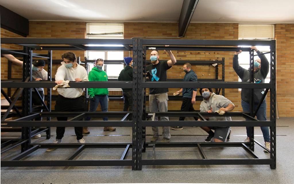 Volunteers, staff and other groups clean and build shelving units in the new Granite Falls Food Bank building Tuesday. (Andy Bronson / The Herald)