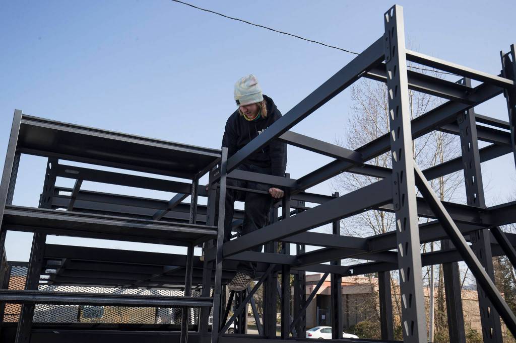 Joe Bradwisch, of Rad Junk Removal, climbs out from between shelving units as he helps move the Granite Falls Food Bank from its old location to a new one Tuesday. (Andy Bronson / The Herald)