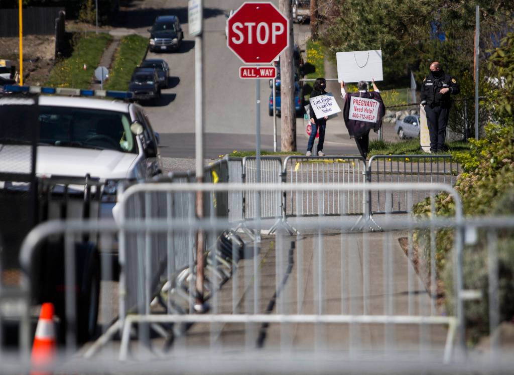 Pro-life supporters stand on the corner of Hoyt Avenue and 32nd Street in Everett on Wednesday, across from fencing around Planned Parenthood. (Olivia Vanni / The Herald)