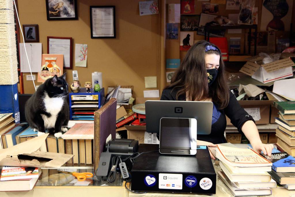 Emily Newman, here with helper Miranda the cat, bought Main Street Books in Monroe in 2012. (Kevin Clark / The Herald)