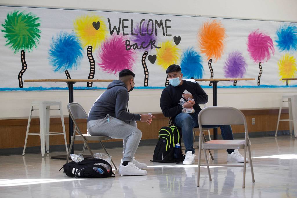 Angel Bermudez and his brother, Manuel, chat over lunch during the first day of in-person school at Everett High on Monday. (Andy Bronson / The Herald)