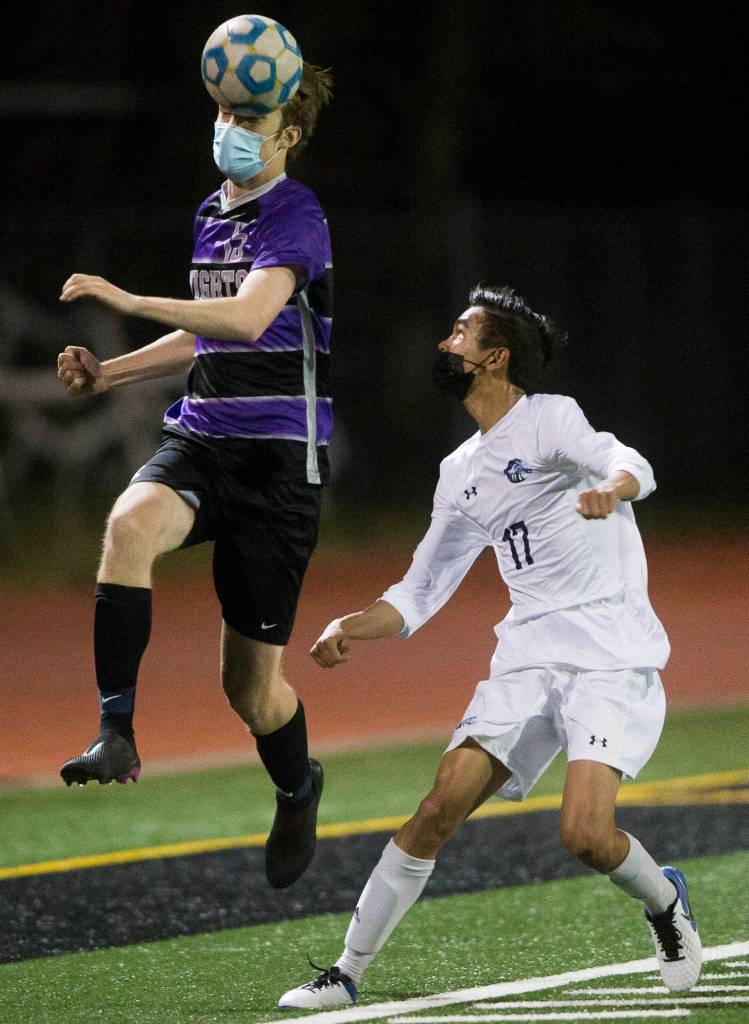 Kamiaks Trace Mohr (left) heads the ball past Meadowdales Tristan Angeles during a game on April 16, 2021, in Mukilteo. (Olivia Vanni / The Herald)