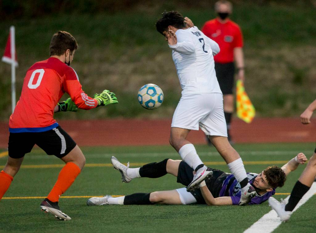 Kamiaks Alexander Hristov (bottom) watches after going down in the goal box as Meadowdale goaltender Avary Olson (0) reaches for the ball during a game on April 16, 2021, in Mukilteo. (Olivia Vanni / The Herald)
