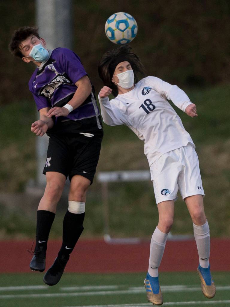 Kamiaks Charlie Soukup (left) and Meadowdales Theo Uherka Hartman jump up to head the ball during a game on April 16, 2021, in Mukilteo. (Olivia Vanni / The Herald)