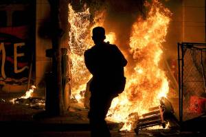Protesters lit a portable bathroom on fire in downtown Portland, Ore., Friday, April 16, 2021. Police in Portland, Oregon, said Saturday they arrested four people after declaring a riot Friday night when protesters smashed windows, burglarized businesses and set multiple fires during demonstrations that started after police fatally shot a man while responding to reports of a person with a gun. (Dave Killen/The Oregonian via AP)