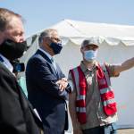Gov. Jay Inslee speaks with pod manager Peyton Plucker at the mass vaccination site at Arlington Municipal Airport on Tuesday. (Olivia Vanni / The Herald)