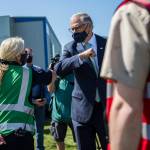 Gov. Jay Inslee greets South County firefighter Nicole Picknell during his visit to the COVID-19 vaccination site at Arlington Municipal Airport on Tuesday. (Olivia Vanni / The Herald)