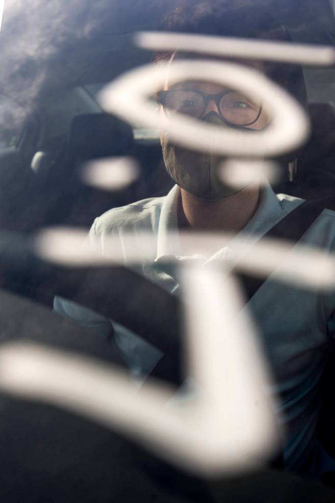 A time is written on the windshield of Herald reporter Joey Thompsons car to help volunteers monitor the wait time after he got his first shot of the Pfizer COVID-19 vaccine at the Ash Way Park & Ride site Wednesday in Lynnwood. (Andy Bronson / The Herald)
