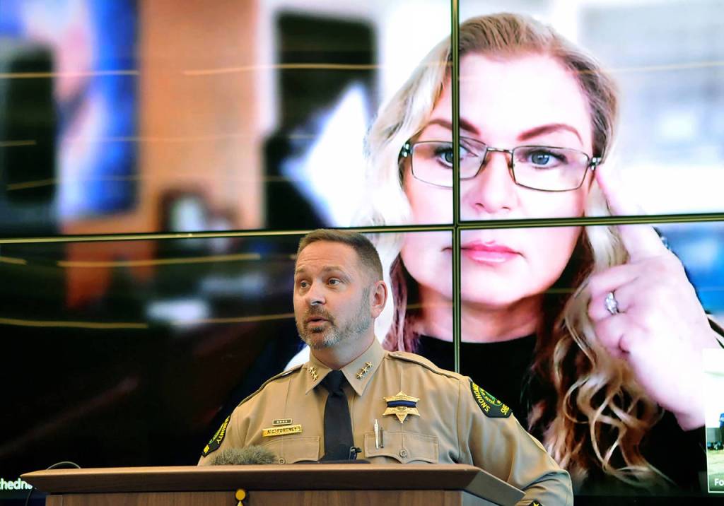 Snohomish County Sheriff Adam Fortney speaks to media July 29, 2020 about the identification of Alan Dean, a suspect in the killing of Melissa Lee, with genetic genealogist CeCe Moore participating over Skype on the screen behind him. (Sue Misao / Herald file)