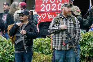 FILE - In this file photo taken Jan. 6, 2021 at the Capitol in Olympia, Wash., two men stand armed with guns in front of the Governor's Mansion during a protest supporting President Donald Trump and against the counting of electoral votes in Washington, DC, affirming President-elect Joe Biden's victory. The open carry of guns and other weapons would be banned on the Washington state Capitol campus and at or near any public demonstration across Washington under a measure that received a remote public hearing Tuesday, Jan. 26, 2021 by the Senate Law and Justice Committee. (AP Photo/Ted S. Warren, File)