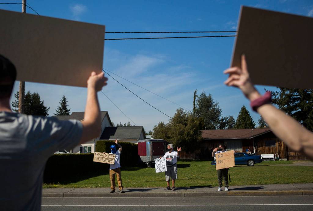 Protestors stand along 80th Street NE in front of the Marysville School District Service Center on Wednesday. (Olivia Vanni / The Herald)