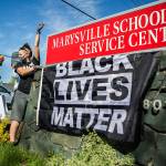 Gus Underfoot hangs a Black Lives Matter flag underneath the Marysville School District sign during a protest on Wednesday, April 21, 2021 in Marysville, Wash. (Olivia Vanni / The Herald)