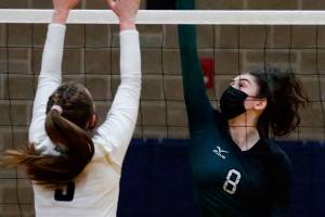 Jackson's Erin Ingram (right) spikes with Arlington's Paige Richards defending Thursday night at Arlington High on March 11, 2021. (Kevin Clark / The Herald)