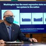 Gov. Jay Inslee sits in front of a chart comparing Washington states tax system to other western states as he talks to reporters last Decemger at the Capitol in Olympia. (AP Photo/Ted S. Warren, file)