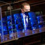Gary Holt, who reads bills being considered in the Washington state House, wears a mask as he sits behind a plexiglass shield, reflecting images of state representatives meeting remotely, April 21, at the Capitol in Olympia Wash. The House was considering a proposed new tax in Washington state on capital gains that would be imposed on the sale of stocks and bonds in excess of $250,000. The legislation was adopted. (Ted S. Warren / Associated Press)