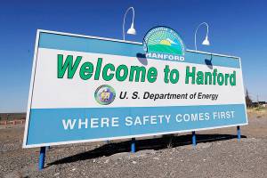 FILE - In this Aug. 13, 2019, file photo, a sign at the Hanford Nuclear Reservation is posted near Richland, Wash. Two companies that do work at the former nuclear weapons production plant will pay fines of nearly $58 million for improperly billing the federal government for thousands of hours of work that were not performed. (AP Photo/Elaine Thompson, File)