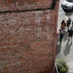 Pedestrians walk beside a brick building on Wetmore Avenue on March 17, 2021, in Everett, Washington. Old buildings constructed before 1945, with unreinforced masonry, are vulnerable to seismic waves. The exterior could break away and plummet into the street. (Andy Bronson / The Herald)