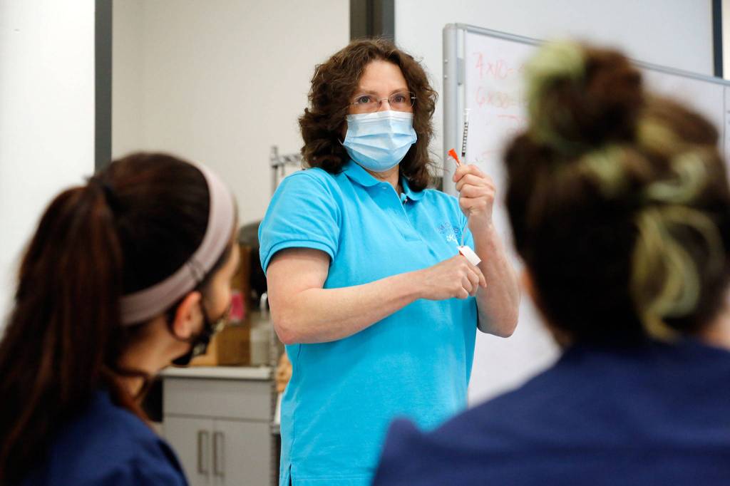 Kyra McCoy, director of nursing, discusses different types of needles during a class at Edmonds College. (Kevin Clark / The Herald)