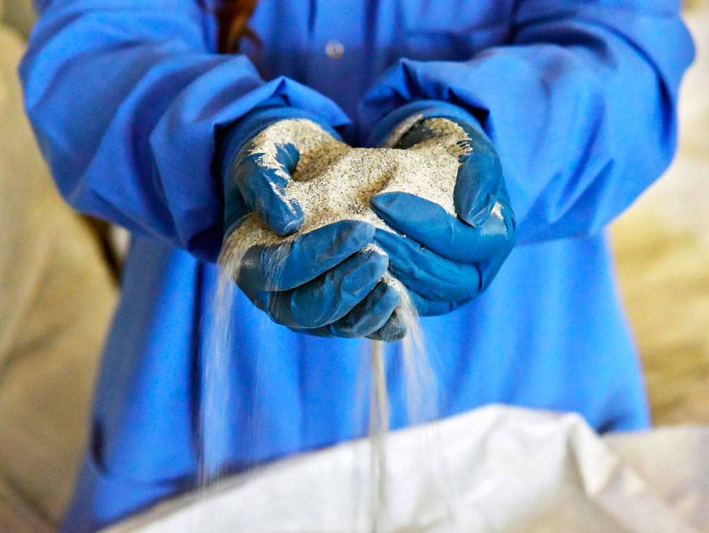 Highland Simulant, a simulated lunar soil made by Off Planet Research, pours from a researchers hands. (Off Planet Research)