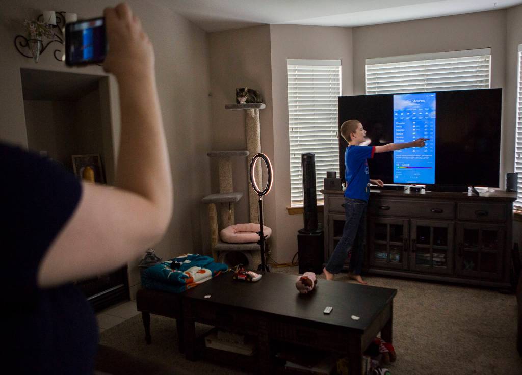 Tonya Stowell records her son David during his daily local weather report. (Olivia Vanni / The Herald)