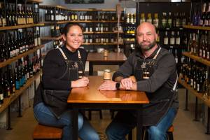 Owners Krista and Eric Brown sit among rows of wines at The Grape & Grain, a new independent beer and wine store on Evergreen Way, on Wednesday, April 28, 2021 in Everett, Washington.  (Andy Bronson / The Herald)