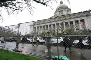 FILE -  In this Jan. 11, 2021 file photo, members of the Washington National Guard stand near a fence surrounding the Capitol in anticipation of protests on the first day of the 2021 legislative session in Olympia, Wash. The 2021 session of the Washington Legislature ended Sunday, April 25 and lawmakers had no shortage of weighty topics to consider while having to conduct their work amid a pandemic that meant most meetings and votes were conducted remotely. The Capitol building was also closed to the public since last year due to the COVID-19 pandemic, and was surrounded by security fencing and national guard members at times due to fears of protests. (AP Photo/Ted S. Warren, File)