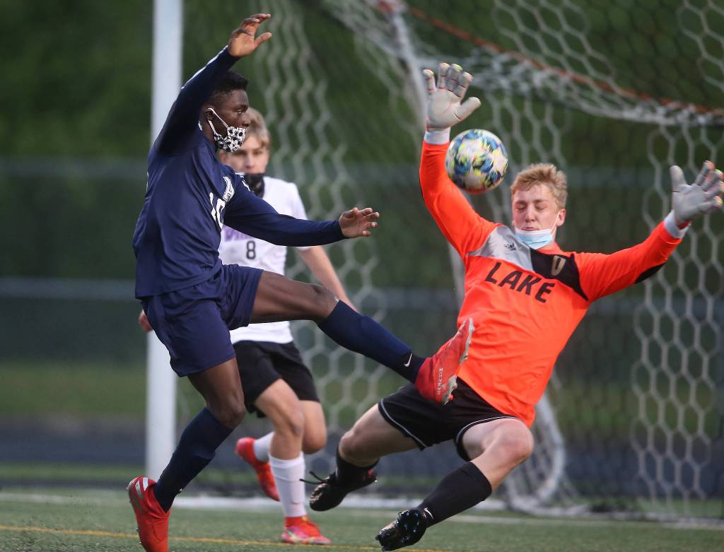 Arlingtons Ferley Cork, left, takes a shot at the goal as Lake Stevens Tanner Jordan runs out of the goal to try and block the kick. Arlington beat Lakes Stevens 2-1 in a boys soccer match on Monday, May 3, 2021 in Arlington, Washington. (Andy Bronson / The Herald)