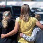 People embrace outside after a shooting at Rigby Middle School in Rigby, Idaho on Thursday, May 6, 2021.  Authorities say a shooting at the eastern Idaho middle school has injured two students and a custodian, and a female student has been taken into custody. (John Roark /The Idaho Post-Register via AP)