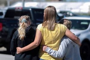 People embrace outside after a shooting at Rigby Middle School in Rigby, Idaho on Thursday, May 6, 2021.  Authorities say a shooting at the eastern Idaho middle school has injured two students and a custodian, and a female student has been taken into custody. (John Roark /The Idaho Post-Register via AP)