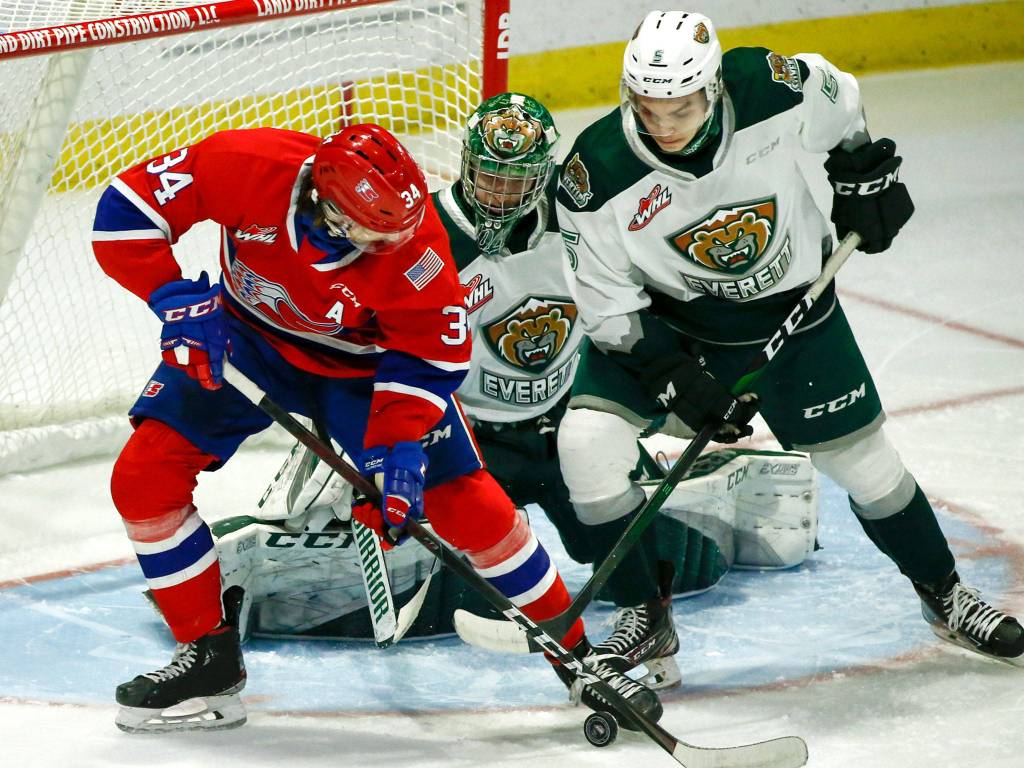 The Chiefs Adam Beckman (left) and the Silvertips Zach Ashton struggle for the puck in front of the Silvertips Dustin Wolf during a game on May 7, 2021, at Angel of the Winds Arena in Everett. (Kevin Clark / The Herald)