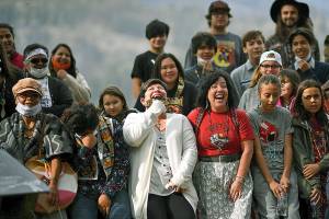 Linda Desautel, center in white, looks skyward and cheers with friends and Colville Confederated Tribe members as they rally in support of her husband Rick Desautel, whose case in the Canadian Supreme court arguing for the Sinixt peoples' right to hunt traditional lands in Canada was first heard, on Thursday, Oct. 8, 2020, near Kettle Falls, Wash. It's been 50 years since the Confederated Tribes of the Colville Reservation voted against termination, effectively ending the federal government's experiment in abrogating treaties, eliminating funding and "freeing the Indians" from the Bureau of Indian Affairs. More than 100 tribes were terminated by the United States — but not one after the 12 bands that make up the reservation in Washington state crushed the idea at the ballot box. (Tyler Tjomsland/The Spokesman-Review via AP)