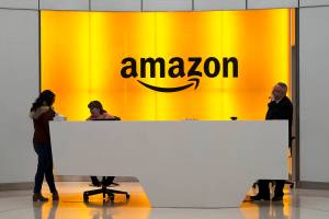 FILE - In this Feb. 14, 2019, file photo, people stand in the lobby for Amazon offices in New York. Amazon, which has been under pressure from shoppers, brands and lawmakers to crack down on counterfeits on its site, said Monday, May 10, 2021, that it blocked more than 10 billion suspected phony listings last year before any of their offerings could be sold. (AP Photo/Mark Lennihan, File)