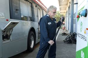 Craig Jacobsen, a technician at Everett Transit, demonstrates how the electric buses are charged. The new system takes about four hours to charge the batteries. (Lizz Giordano / The Herald)
