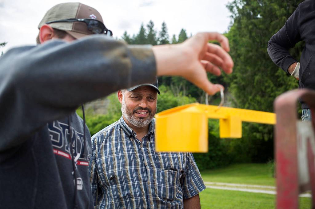 Spencer Fuentes watches as Nick Schultheis, a Field Representative with Farmer Bean & Seed, uses a scale to estimate the number of black beans produced per acre, May 12 in Arlington. (Andy Bronson / The Herald)
