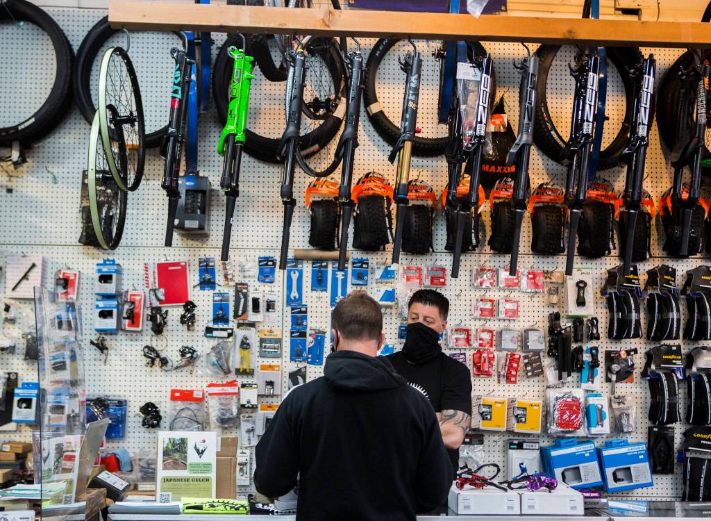 Jay Hiester, owner of Tims Bike Shop, helps a customer pick out a rear tire Friday in Everett. (Olivia Vanni / The Herald)
