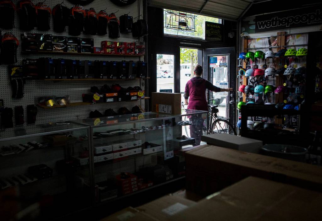 A customer walks out with their bike Friday after getting it serviced at Tims Bike Shop in Everett. The pandemic has been good, if stressful, for bike shops across the county. (Olivia Vanni / The Herald)