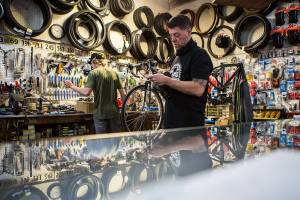 Tim's Bike Shop owner Jay Hiester, right, opens a new bike chain while mechanic Gavin Buchanan, left, looks for tools on Friday, May 21, 2021 in Everett, Wash.