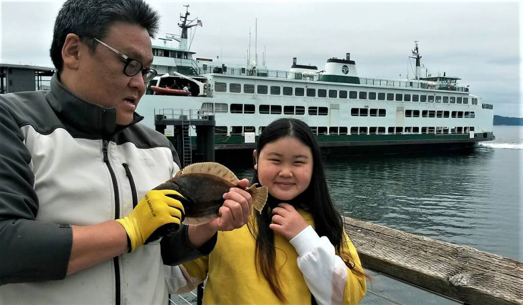 Do Kim and his daughter Allison show off a flounder they caught Sunday at the new fishing pier near the Mukilteo ferry terminal. (Julie Muhlstein / The Herald)