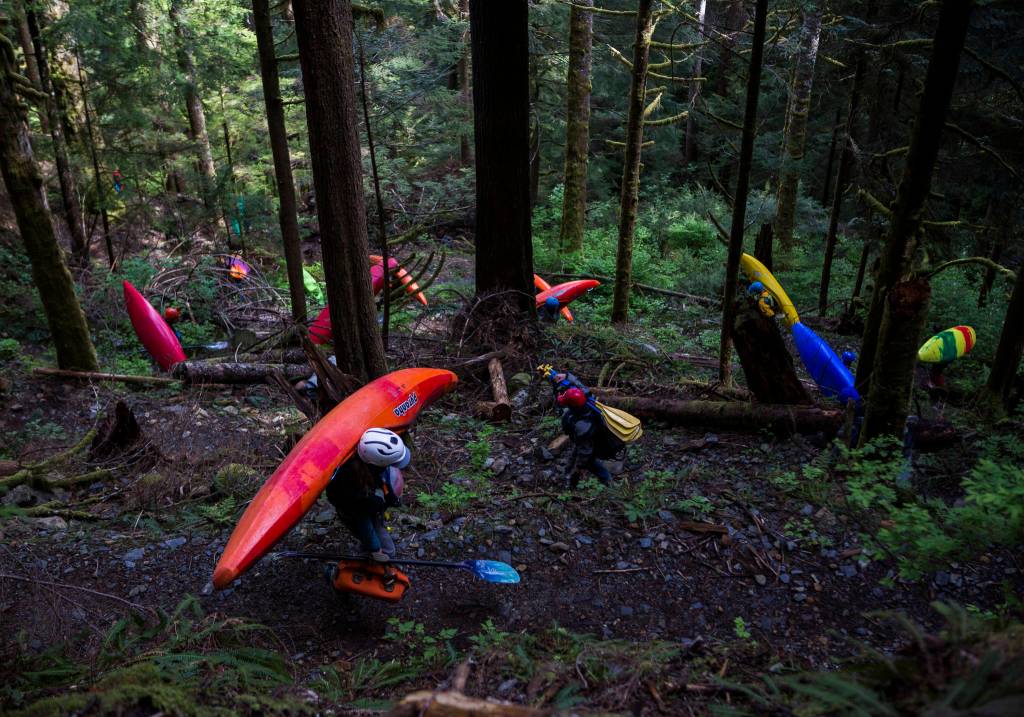 Kayakers carry their dry bags and kayaks down a switchback to get to the Sultan River. (Olivia Vanni / The Herald)