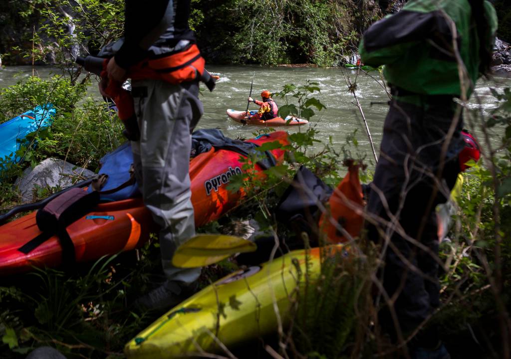 Kayakers prepare for their own runs and watch others make their way down the Sultan River. (Olivia Vanni / The Herald)