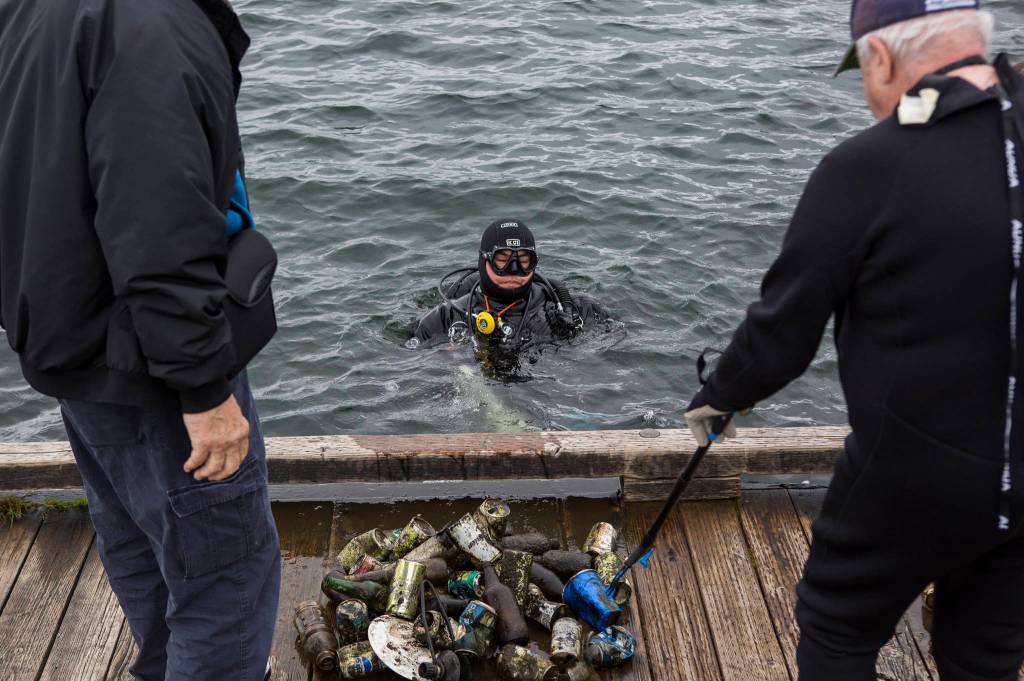 A diver empties trash he collected May 23 onto the dock at Davies Beach in Lake Stevens. He was one of 12 divers and nine others who volunteered to remove garbage from the water. (Olivia Vanni / The Herald)