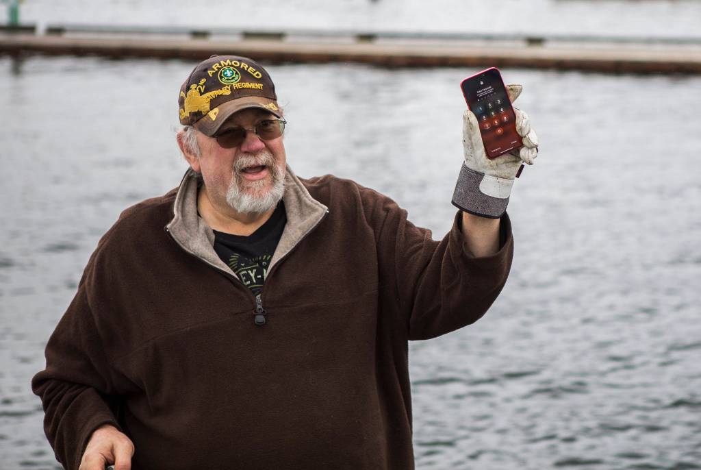 David Hoeft reacts to an iPhone found underwater after powering it on again May 23 in Lake Stevens. (Olivia Vanni / The Herald)